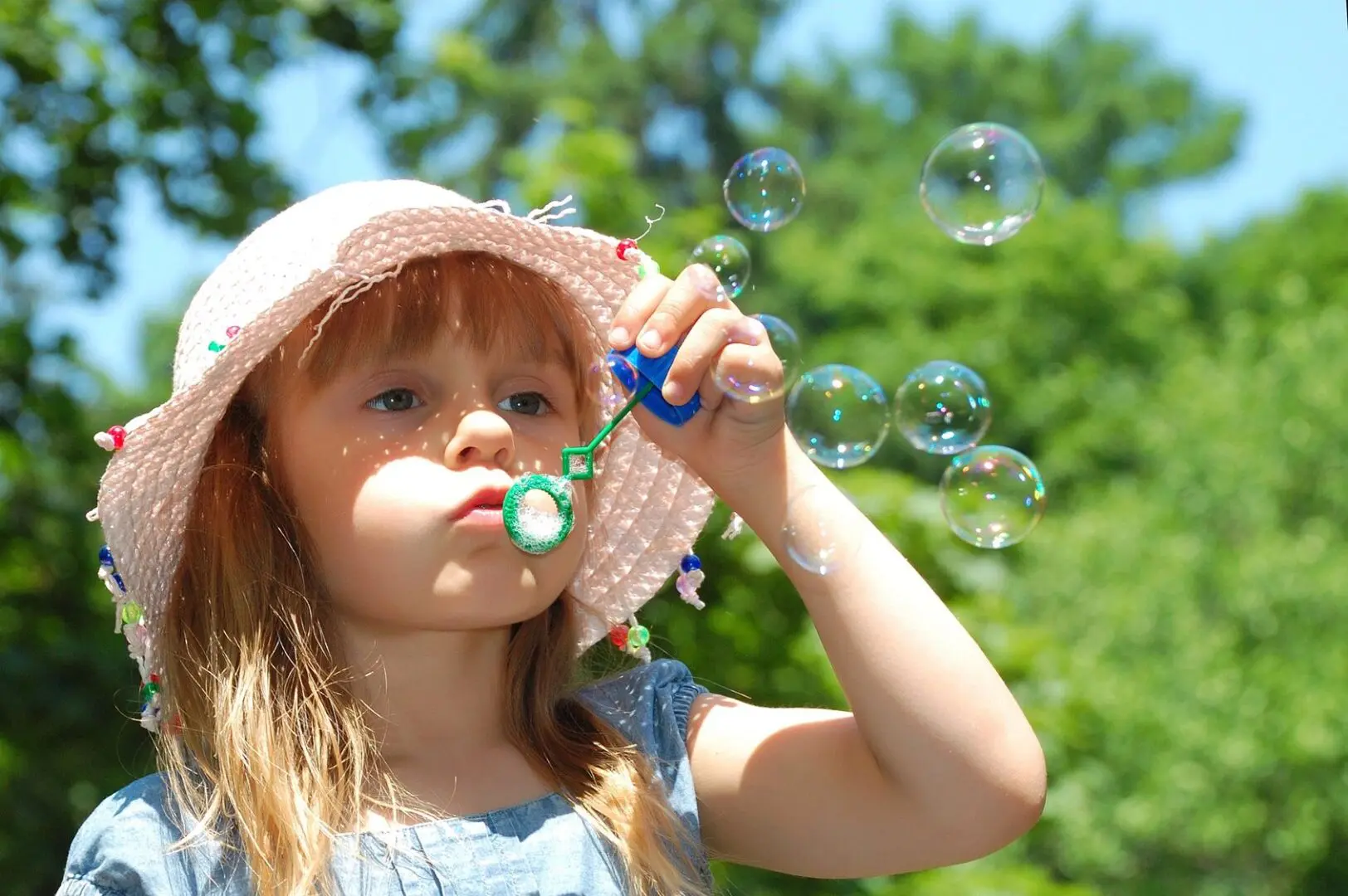 A little girl blowing bubbles with her toy.